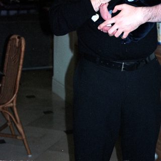 Man holding baby indoors near wooden cabinet.