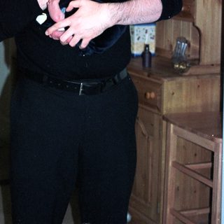 Man holding baby indoors near wooden cabinet.