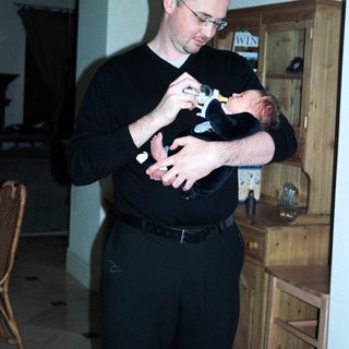 Man holding newborn baby indoors.
