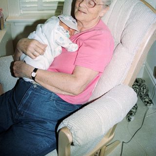 Elderly woman holding sleeping baby indoors.