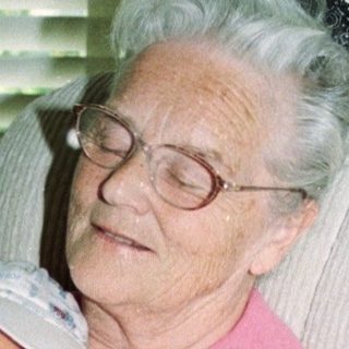 Elderly woman holding sleeping baby indoors.