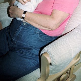 Elderly woman holding sleeping baby indoors.
