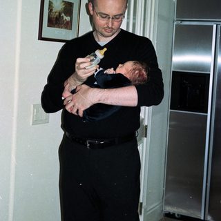 Man holding baby while using phone.