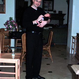 Man holding baby in formal dining room.
