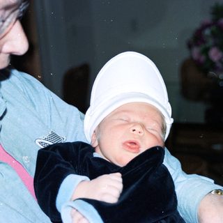 Baby wearing hat being held by adult.