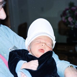 Baby wearing hat being held by adult.