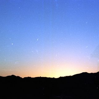 Twilight sky with mountains and visible meteors.