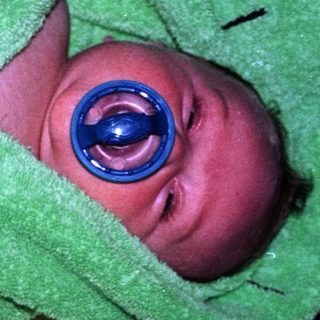 Newborn infant wearing medical eye shield.