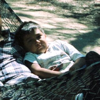 Family relaxing in a hammock outdoors.