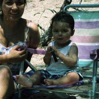 Mother and child relaxing by water.