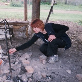 Person feeding goat over fire pit.