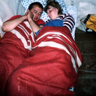 Two people resting together under blankets.