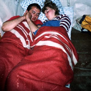 Two people resting together under blankets.
