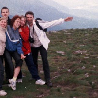 Group posing happily on mountain summit.