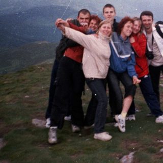 Group posing happily on mountain summit.