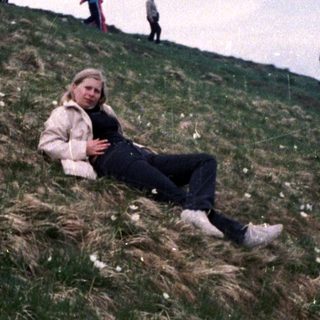 Person relaxing on grassy hillside during outdoor hike.
