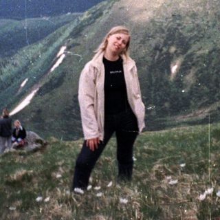 Person standing on mountain peak with scenic valley view.