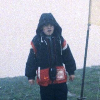Child holding Ukrainian flag on hilltop.