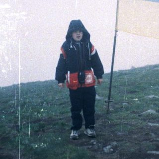 Child holding Ukrainian flag on hilltop.