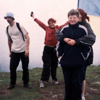 People hiking in misty terrain with flag.