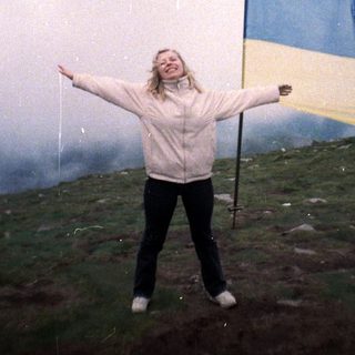 Person holding Ukrainian flag on hilltop.