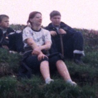Children sitting on grassy hillside.