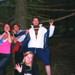 Four people posing under a tree at night.
