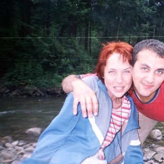 Two people posing happily by a river.
