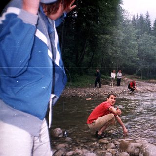 People enjoying outdoor river activity near forest.