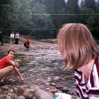 People enjoying outdoor river activity near forest.