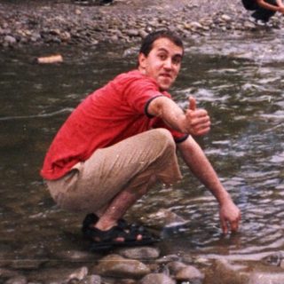 People enjoying outdoor river activity near forest.