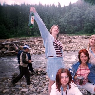 Group celebrating outdoors near river.