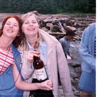 Two women laughing by a river.