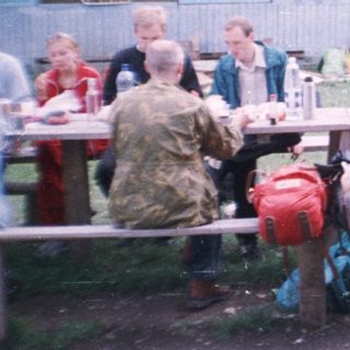 Group picnic or gathering outdoors near rustic buildings.