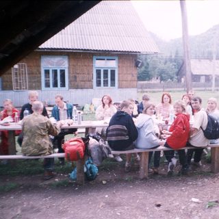 Group picnic or gathering outdoors near rustic buildings.