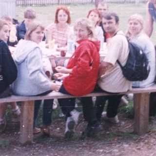 Group picnic or gathering outdoors near rustic buildings.