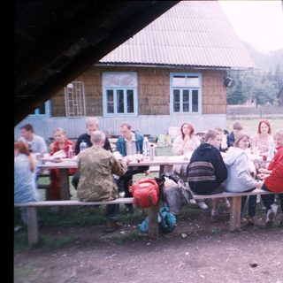 Group picnic or gathering outdoors near rustic buildings.