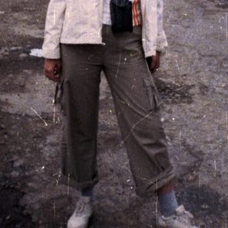 Woman standing outdoors in rural area during rain.