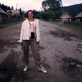 Woman standing outdoors in rural area during rain.