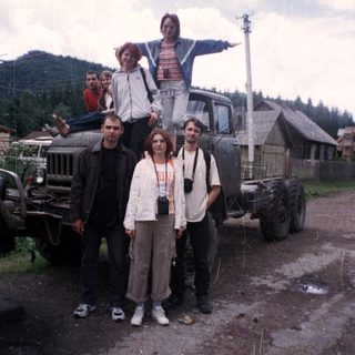 Group posing with vintage truck in rural area.