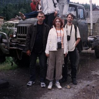 Group posing with vintage truck in rural area.