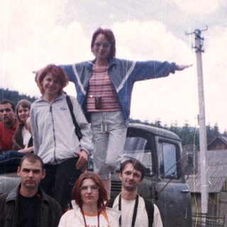 Group posing with vintage truck in rural area.