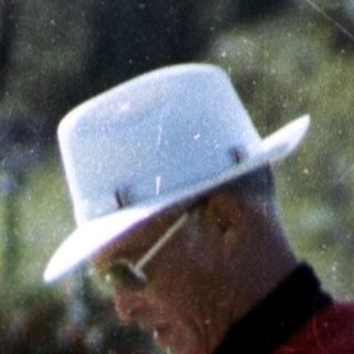 Man in golf attire reading scorecard on green.