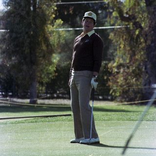 Man playing golf on lush green course.