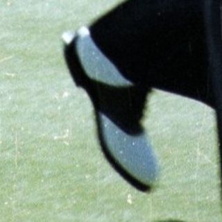 Man playing golf mid-swing on green.