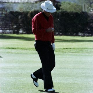 Man playing golf mid-swing on green.