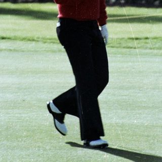Man playing golf mid-swing on green.