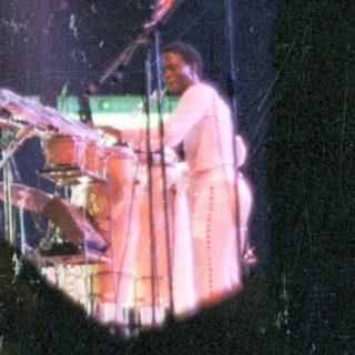 Live band performing on stage with spotlight.
