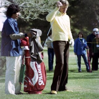 Man taking golf swing on course.