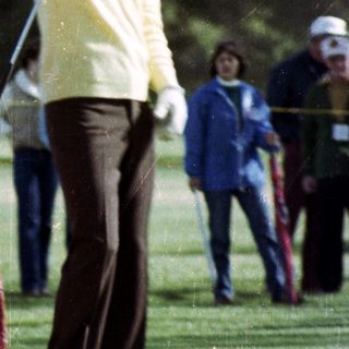 Man taking golf swing on course.